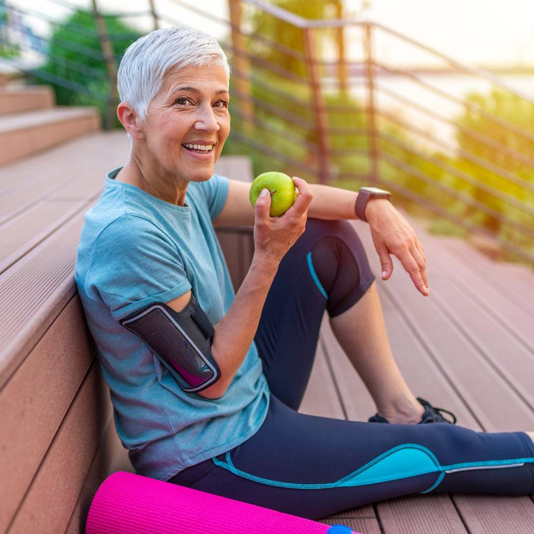 woman eating an apple next to a yoga mat