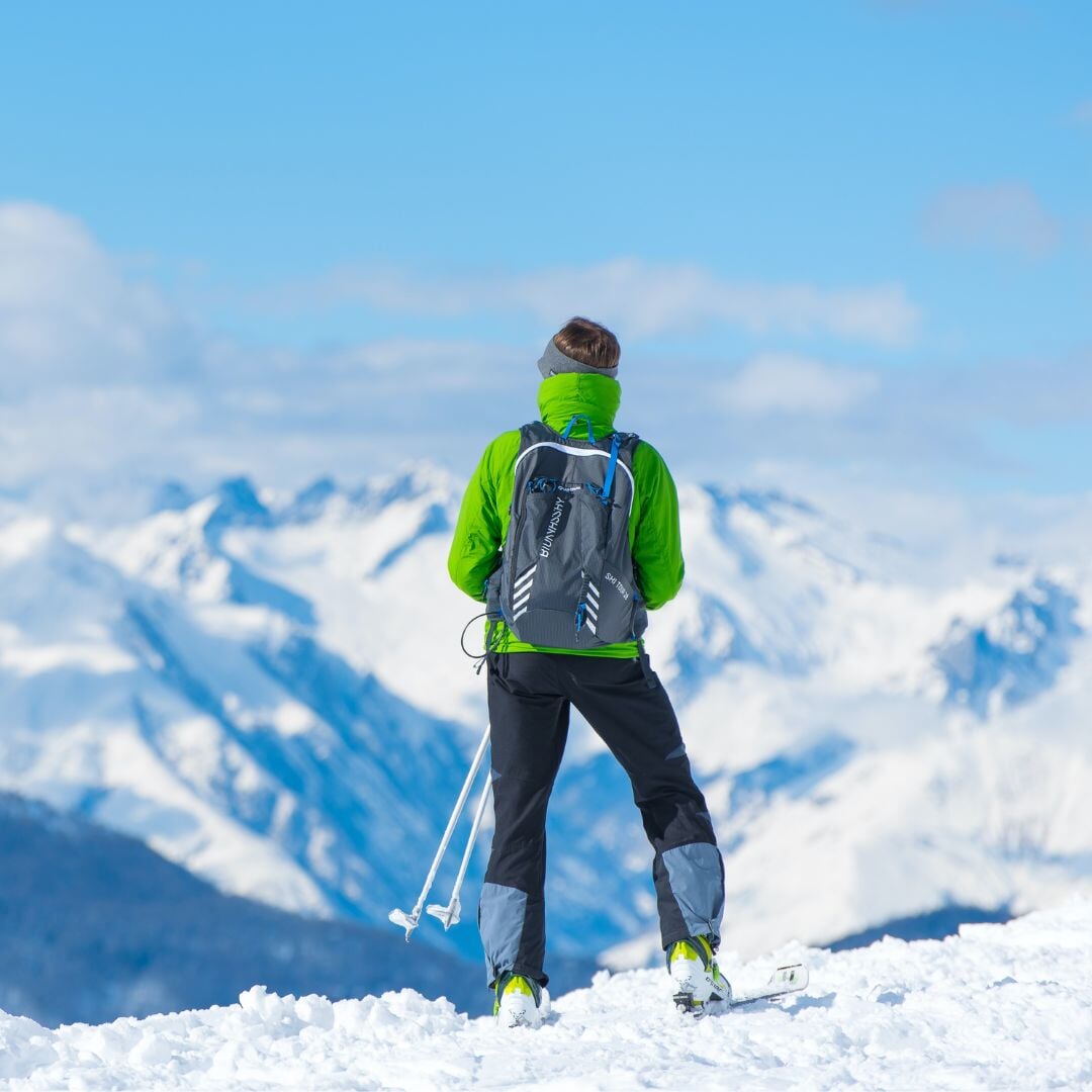 man in ski gear looking at mountains with snow