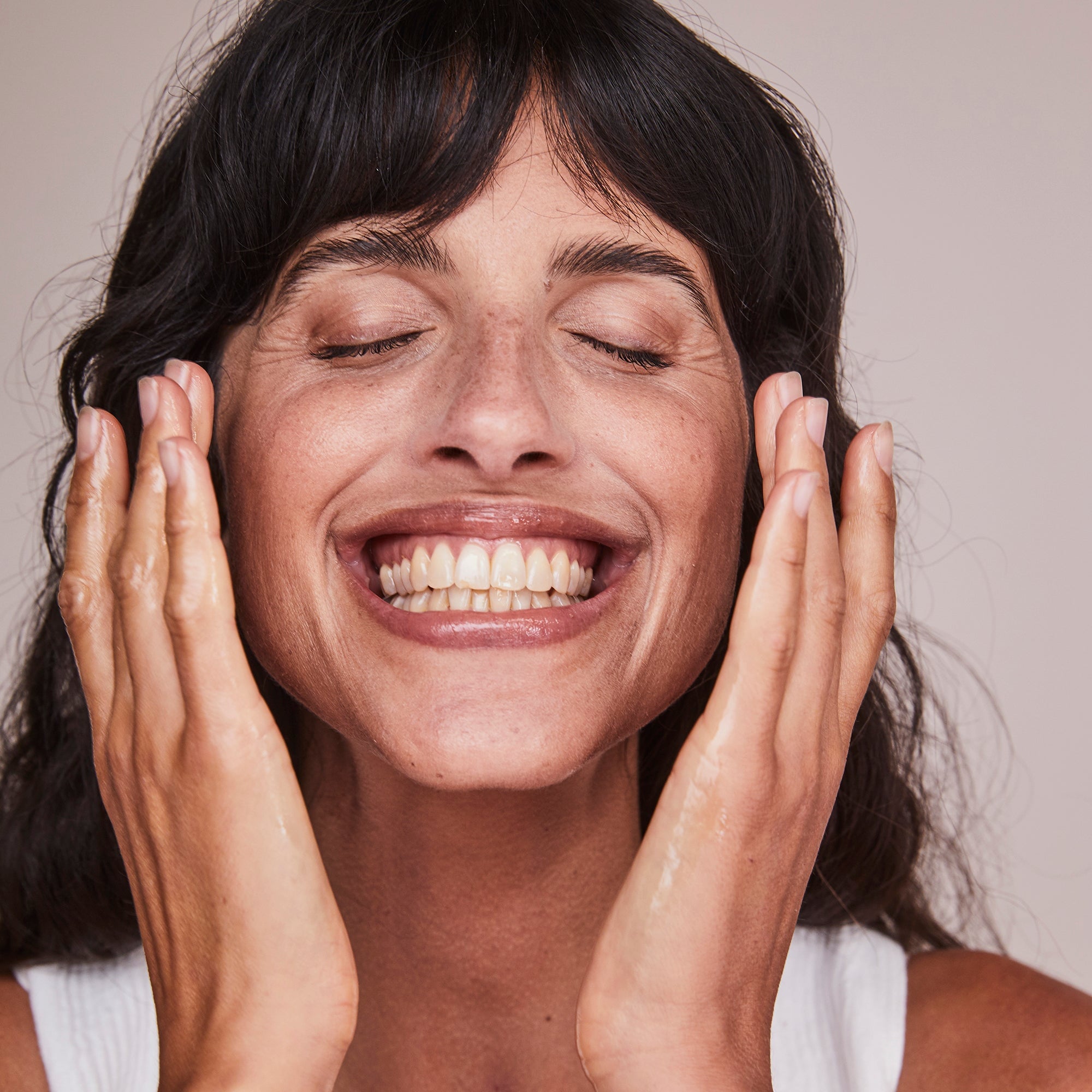 woman touching cheeks with hands smiling
