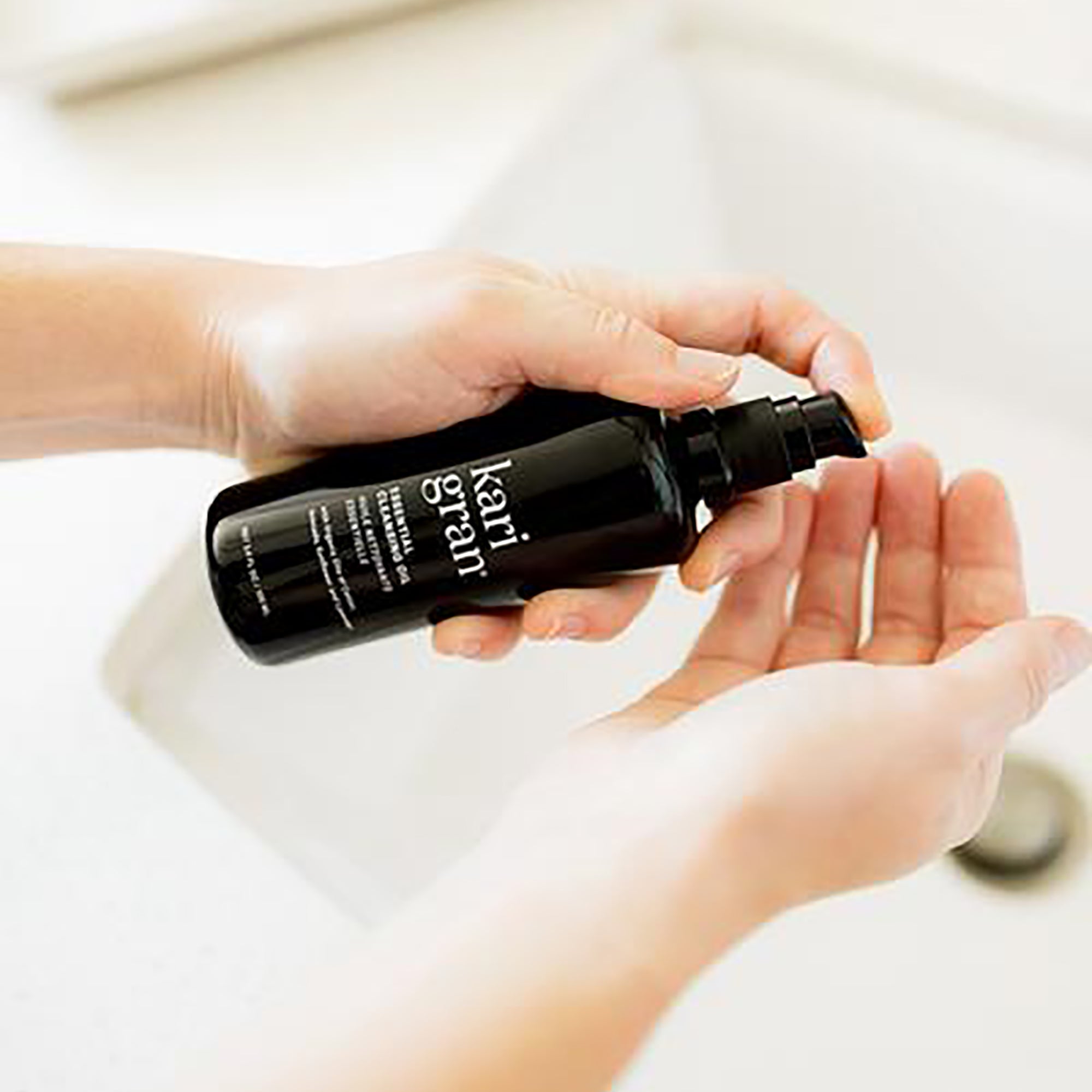 woman putting Kari Gran Cleansing Oil in palm of hand
