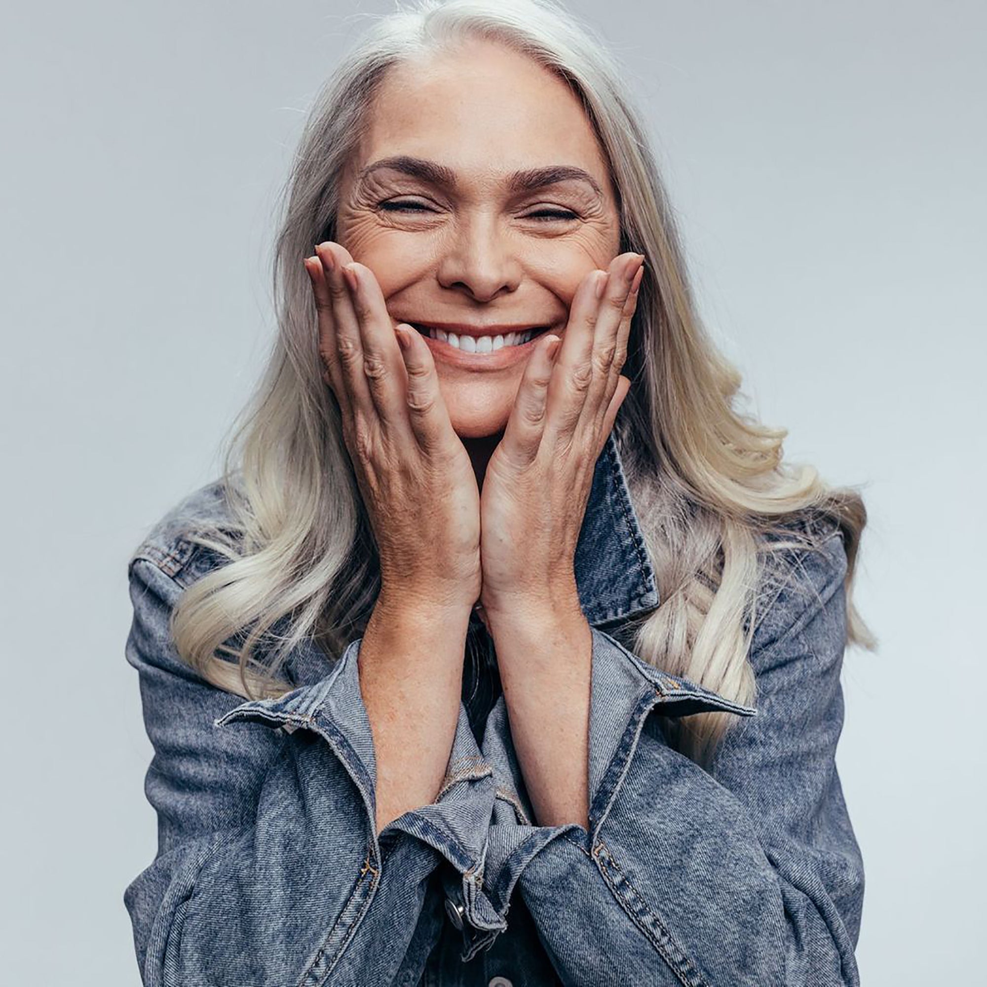 older woman holding face and smiling