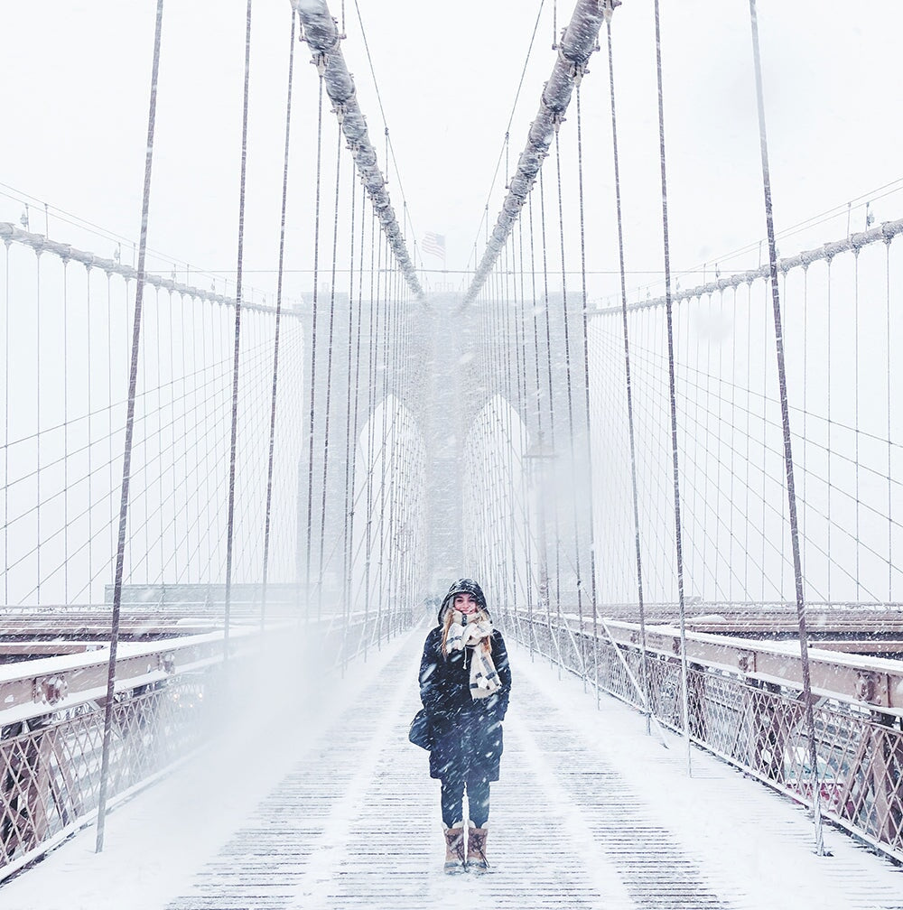 woman walking the brooklyn bridge in snow