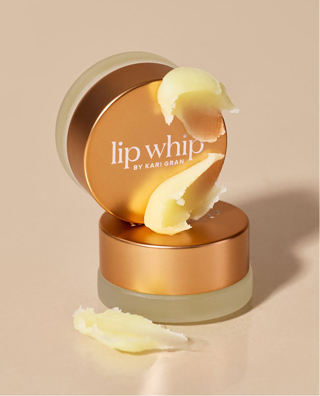 Lip whip by Kari Gran lip balm container with open lid on a beige background