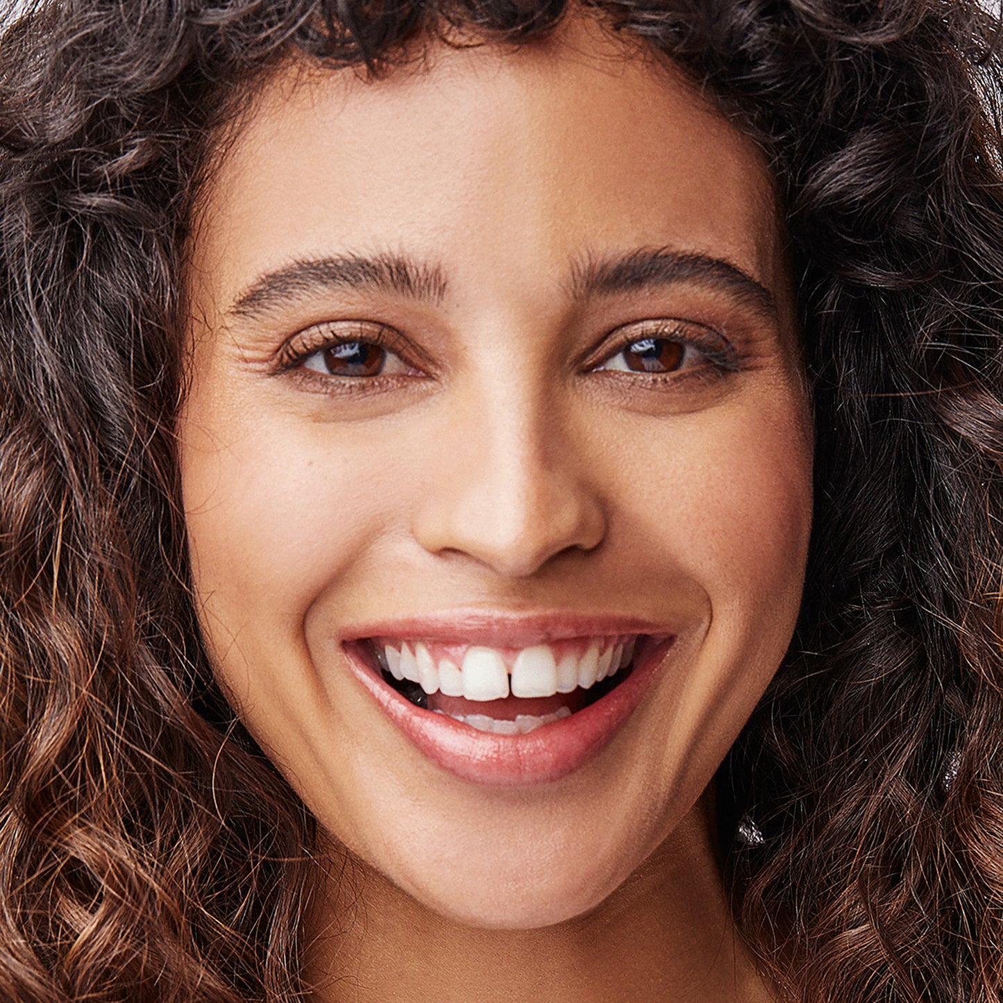 Woman with medium to deep complexion wearing Kari Gran's Cora Gold Lip Whip
