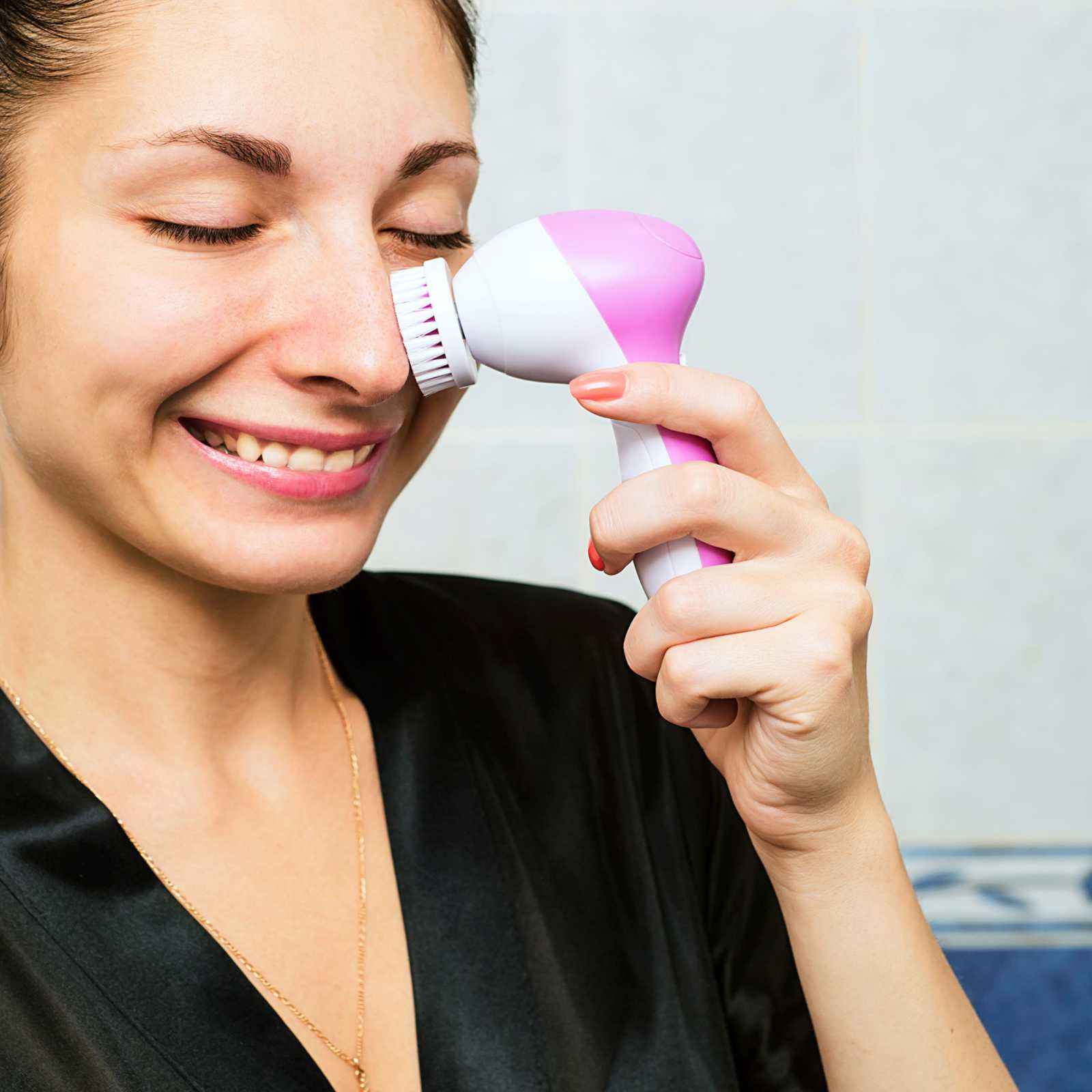 woman using a pink facial cleansing brush
