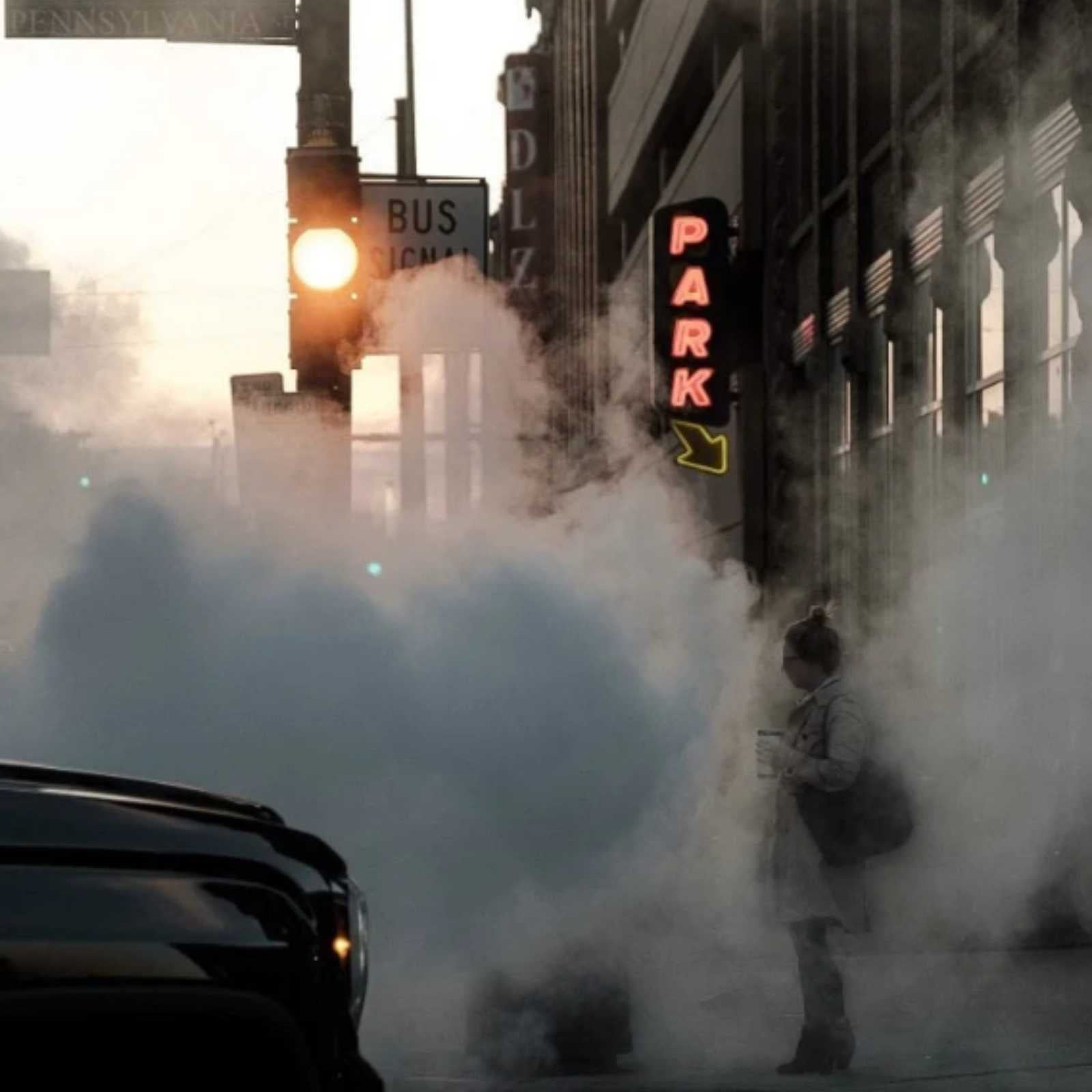 woman standing in exhaust on street corner