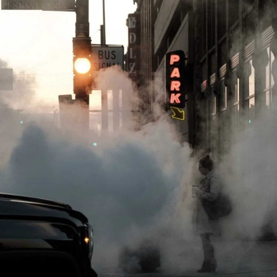 woman standing in exhaust on street corner