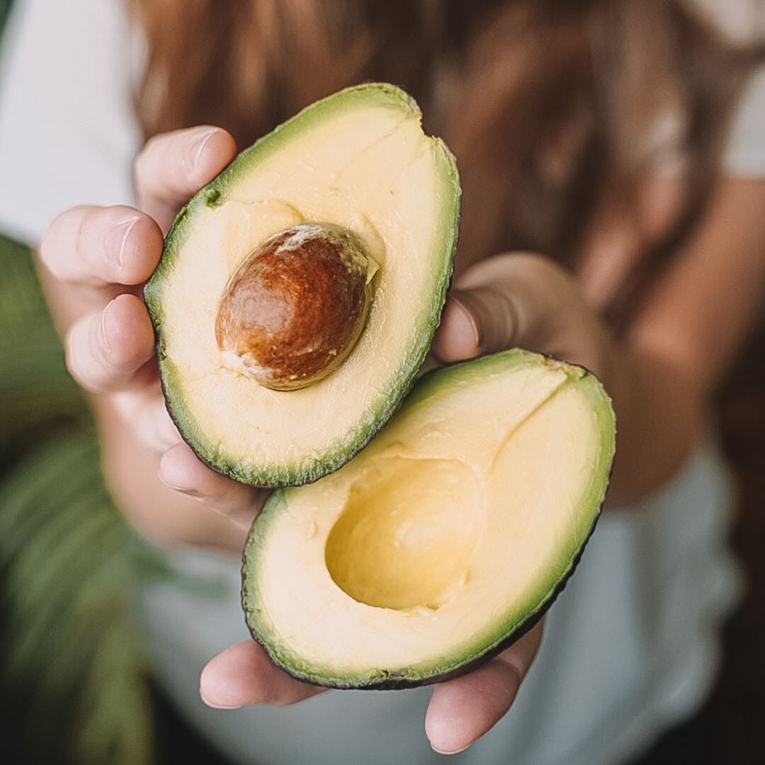 woman holding cut avocados