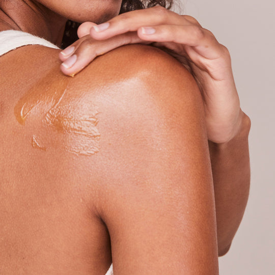 woman placing Kari Gran Essential Serum Balm on shoulder