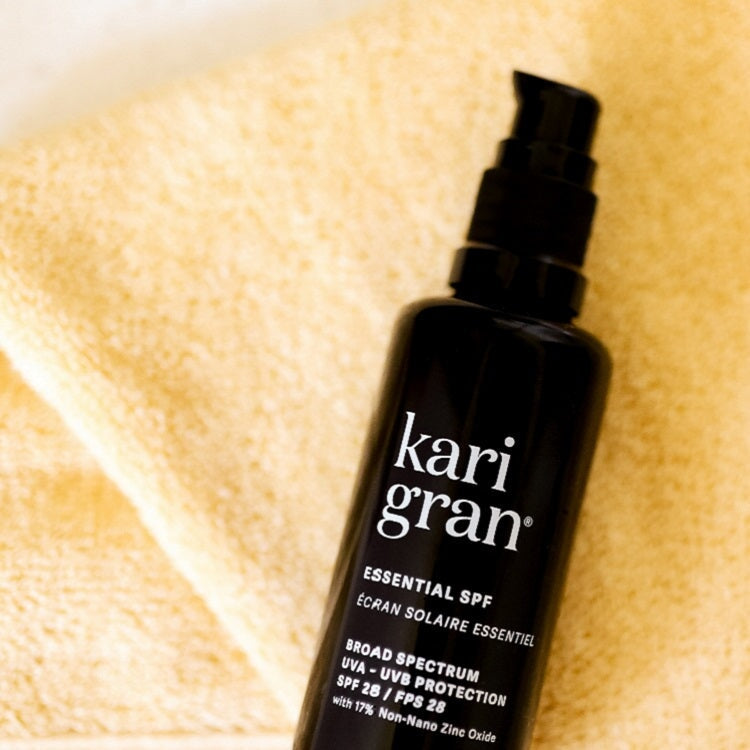 essential spf in 50ml bottle laying on pale yellow towel