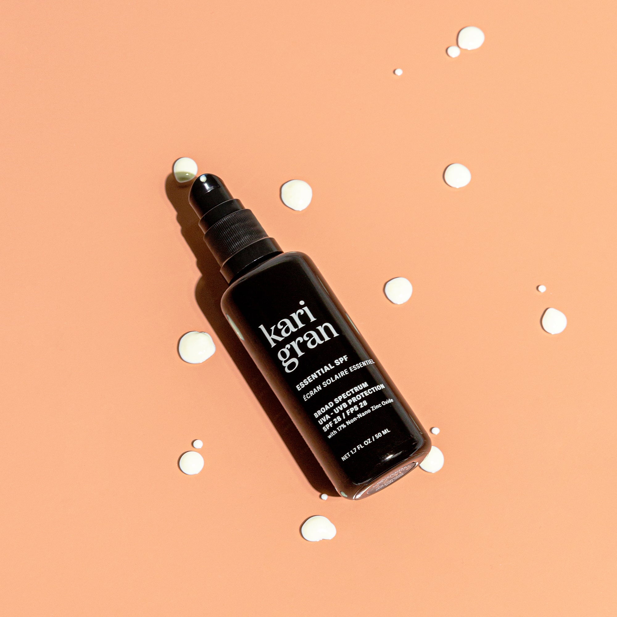 KG Essential SPF with droplets of the product surrounding the bottle
