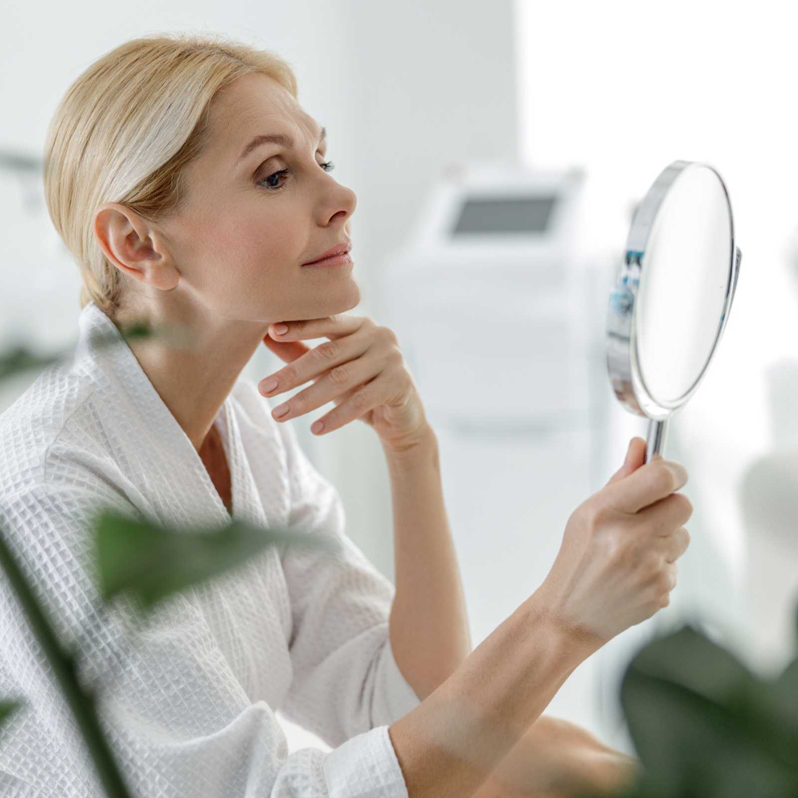 woman looking at herself in a handheld mirror