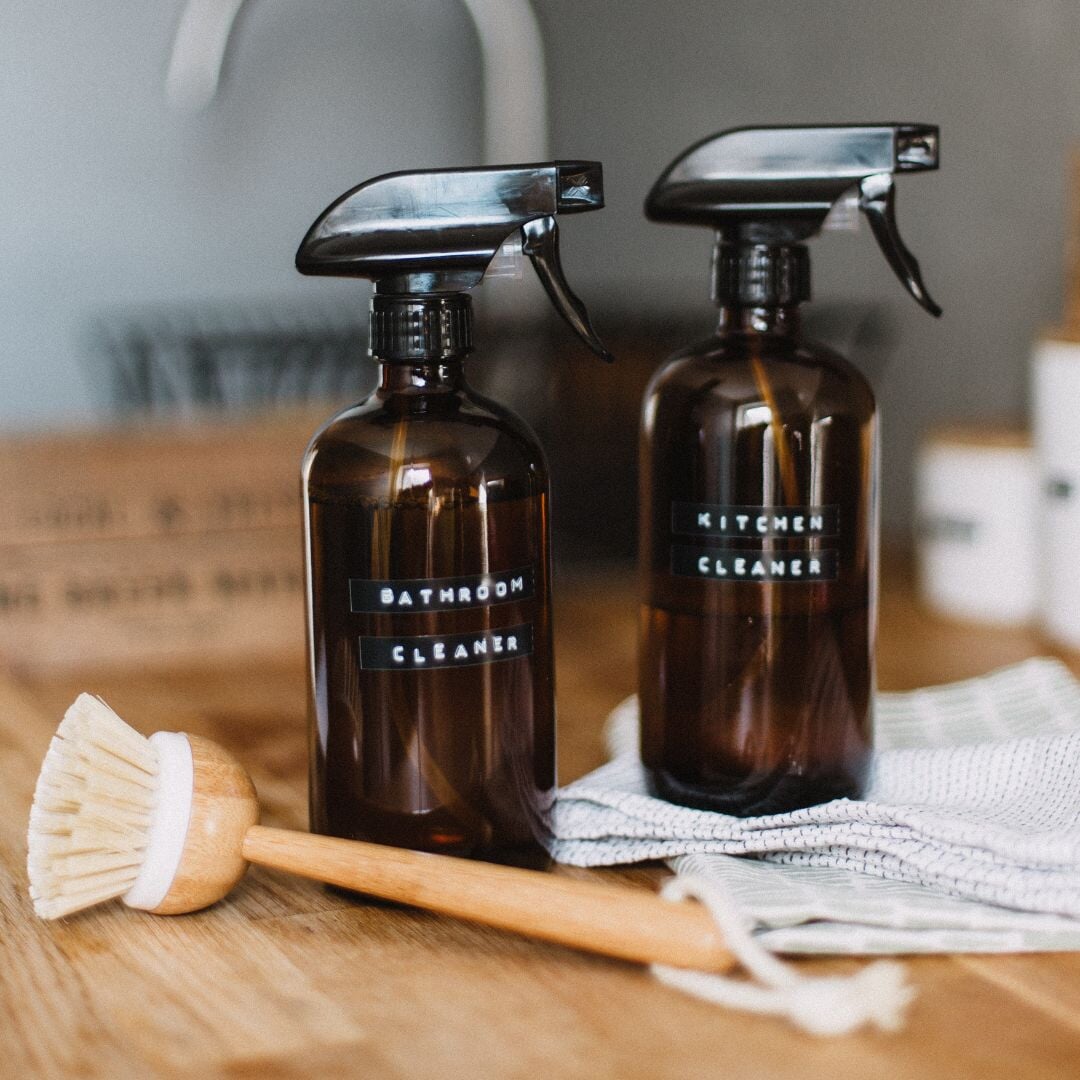 two sprays bottles on cabinet with brush