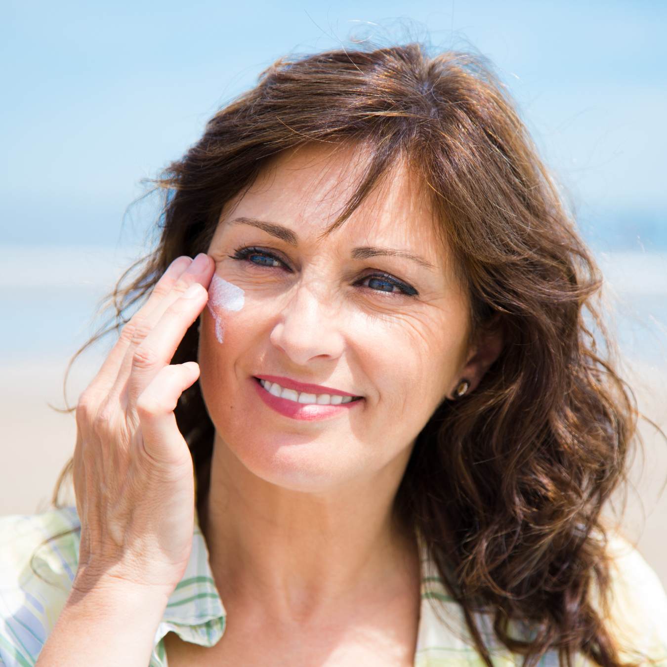 women in her 40s applying sunscreen