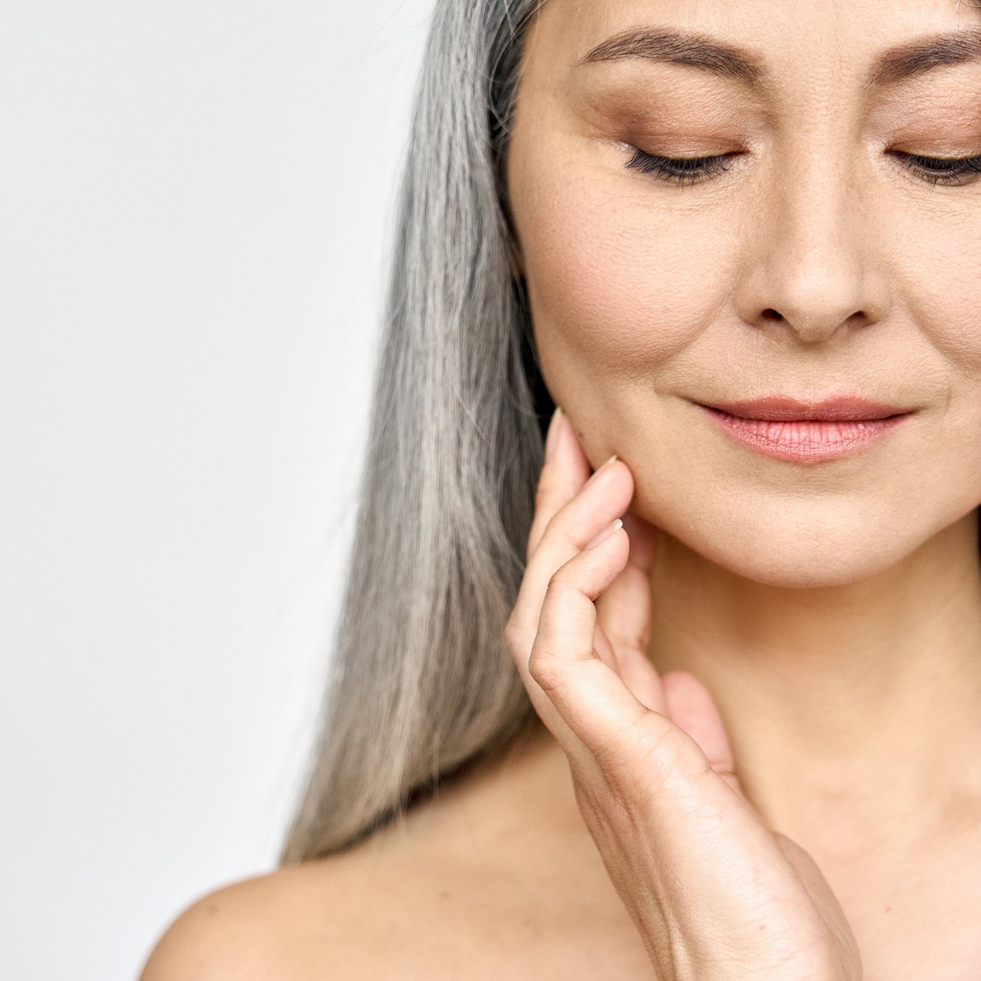 estrogen skincare, woman with gray hair touching her face
