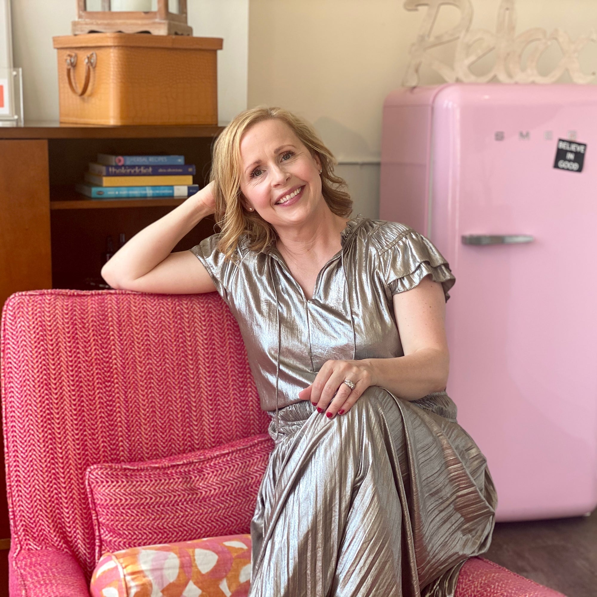 Kari Gran sitting in pink chair wearing a silver dress