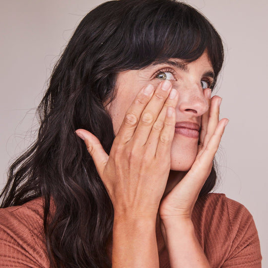 woman touching face and smiling at camera