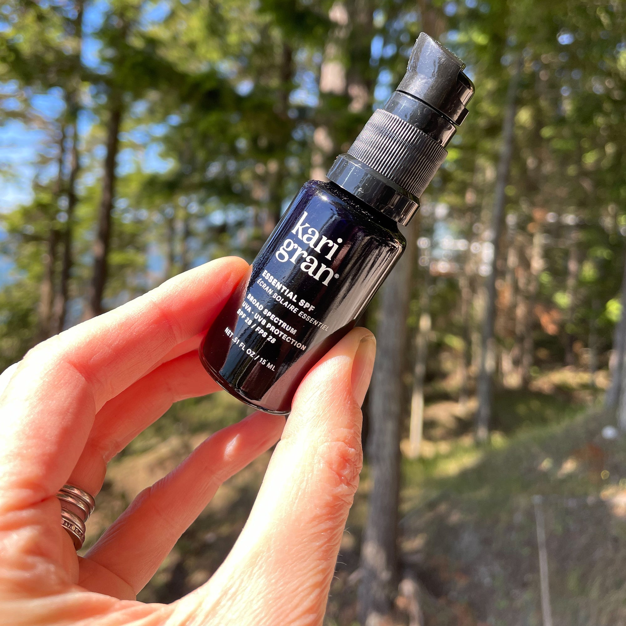 Woman holding a mini size of the KG essential spf in a forest