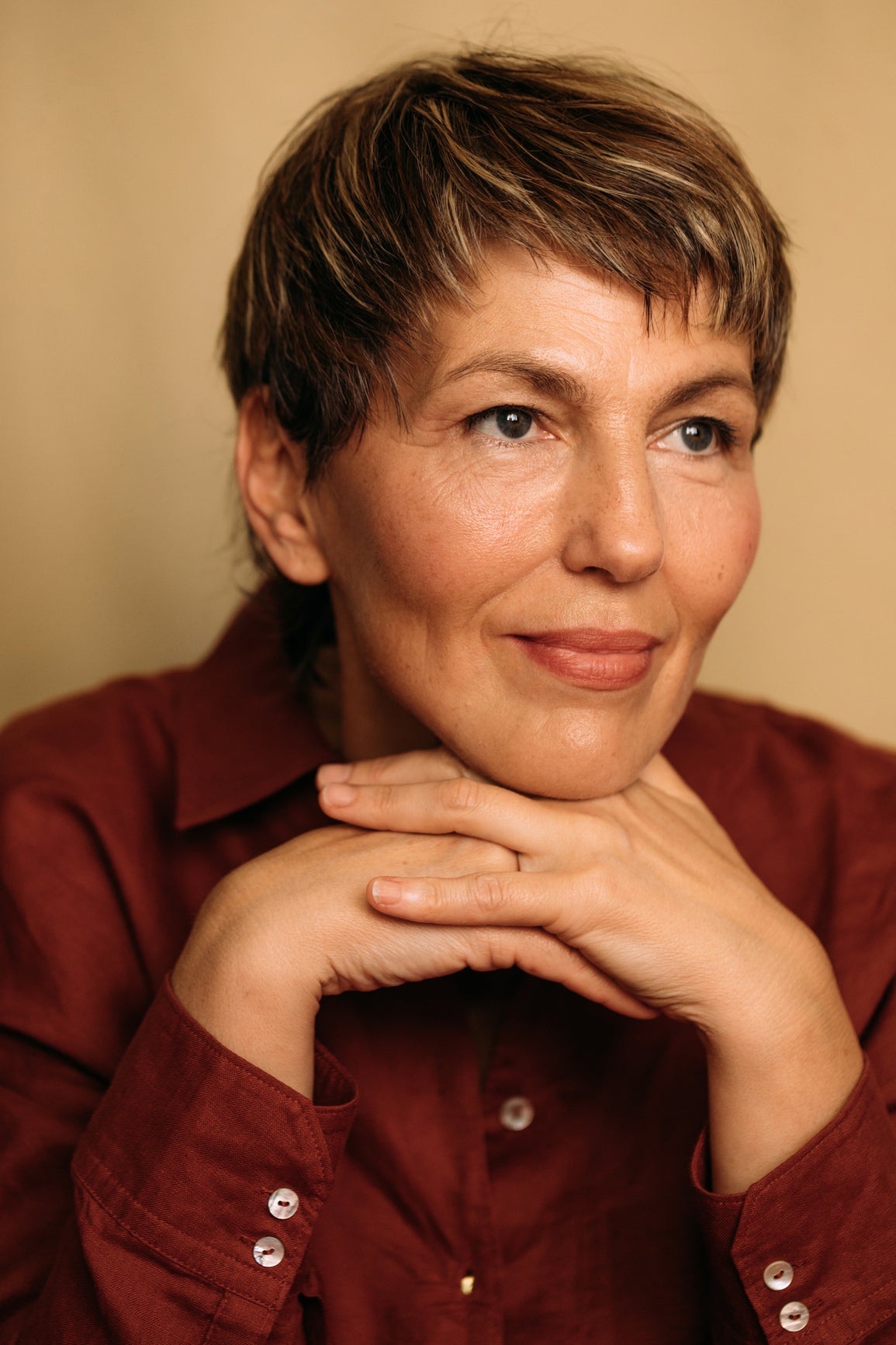 Woman wearing a burgundy shirt with a beige background