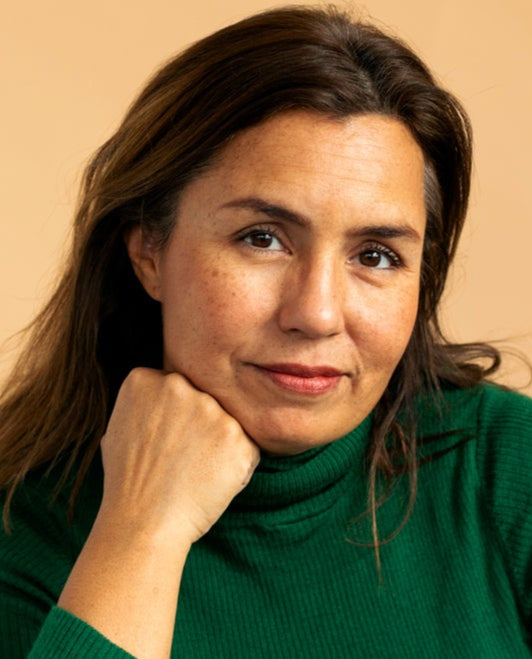 Woman wearing a green turtleneck against a beige background