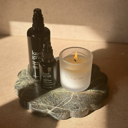 Image of kari gran candle, essential peptide serum and body and bath oil on top of green marble plate
