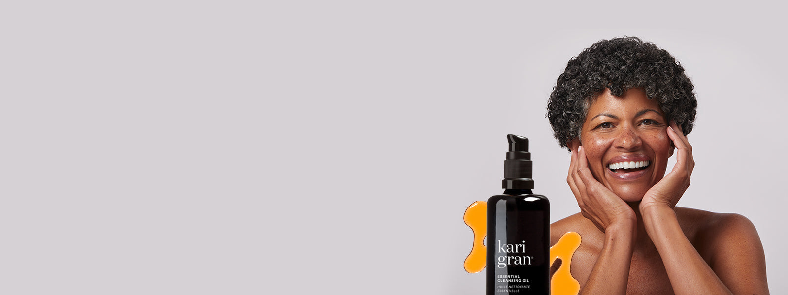 model smiling next to a bottle of the cleansing oil