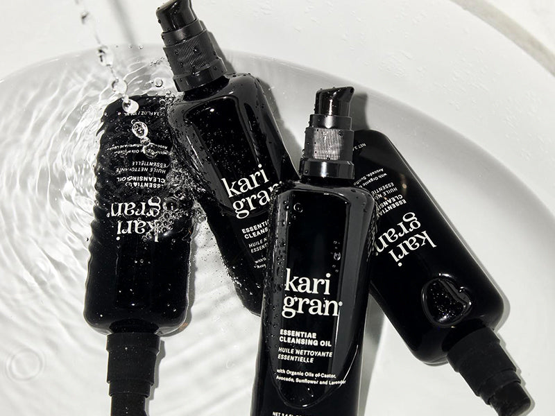 Black and white bottles of Kari Gran hair product on a textured surface
