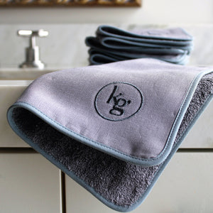 Kari Gran Luxe Exfoliating Washcloth on sink with stack behind