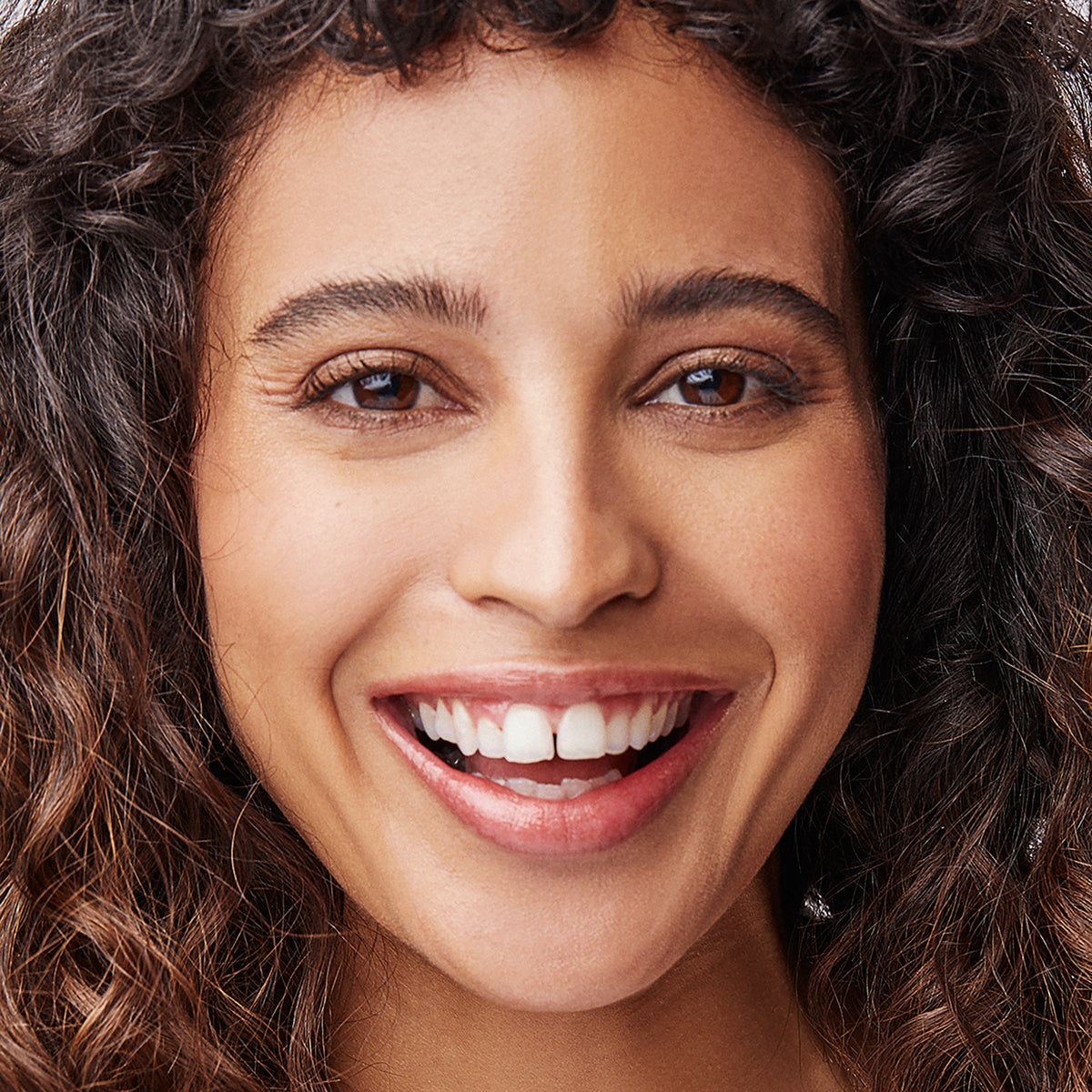 Woman with medium to deep complexion wearing Kari Gran's Cora Gold Lip Whip 